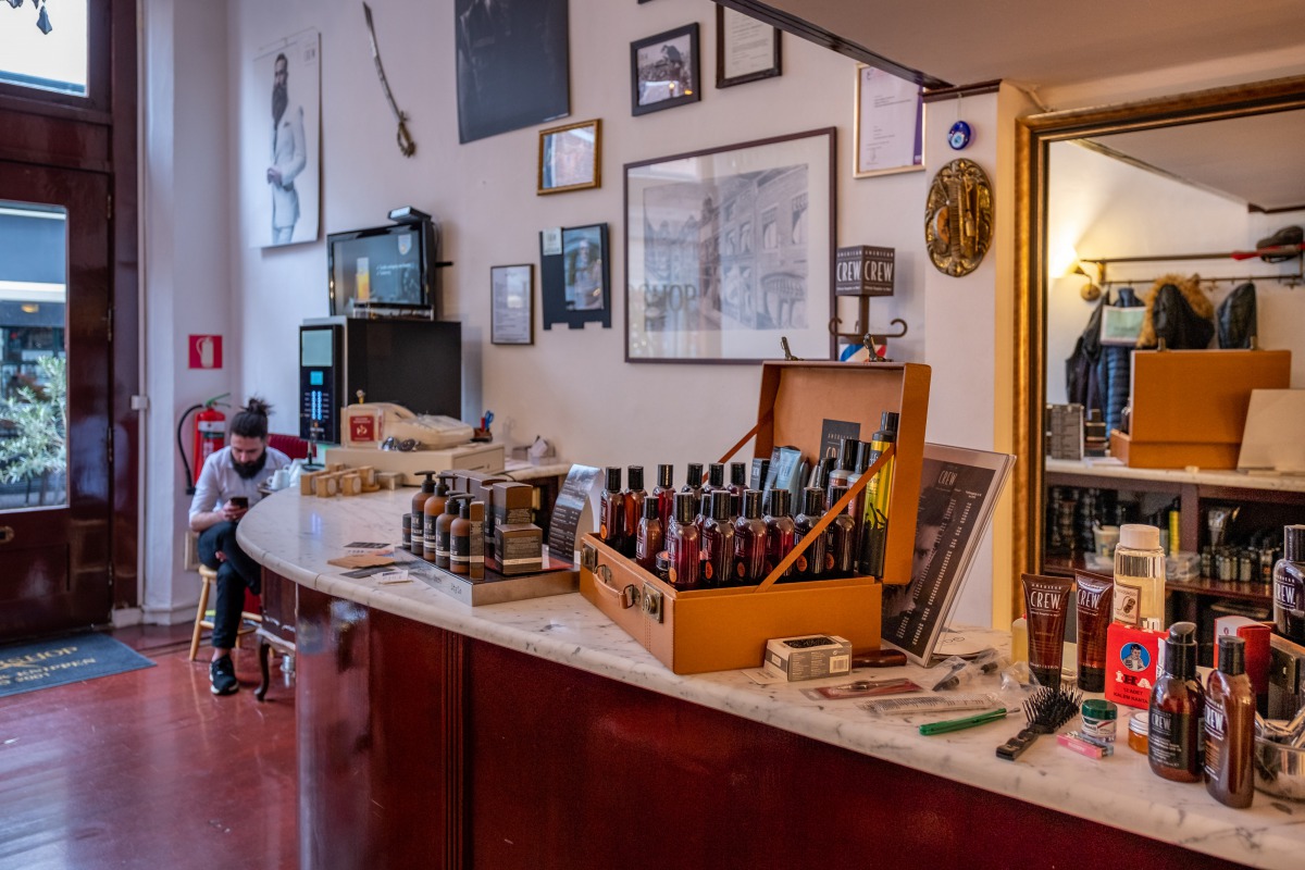 Interieur Sherwany Barbershop: marmeren toonbank, warme verlichting, ingelijste certificaten
